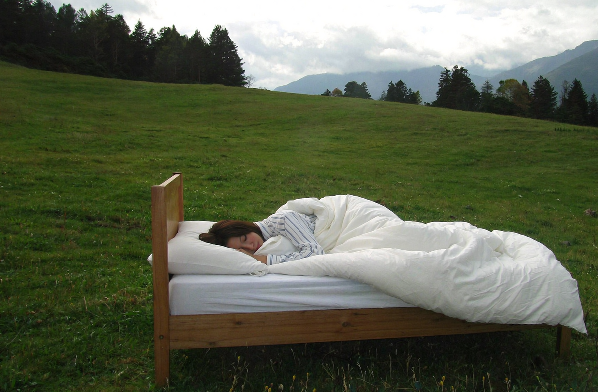 Helles Schlafzimmer in warmen Cremetönen mit dicker Alpaka-Bettdecke, Sonnenlicht durch Vorhänge, Travertinboden